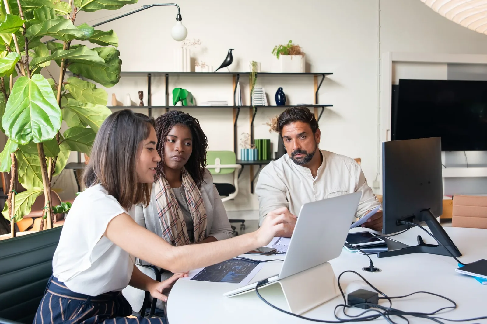 Small ops team reviewing workflow tasks on a laptop and phone in a modern office