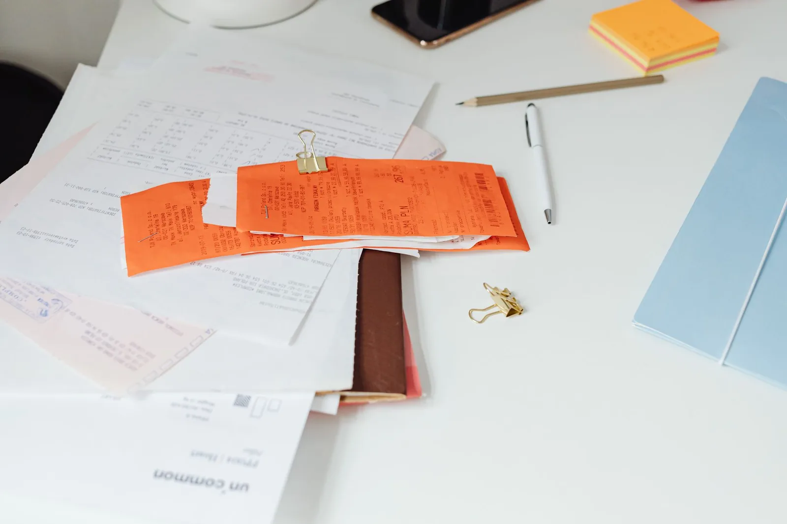 Stack of supplier invoices and quotes next to a laptop running OCR extraction software on the screen