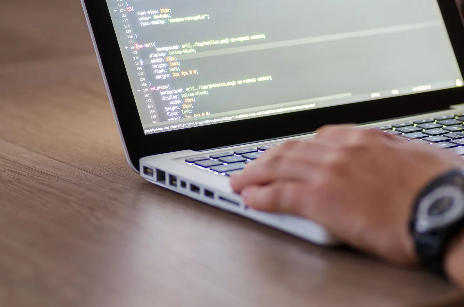 Developer reviewing website audit data and performance metrics on a laptop screen with code editor open