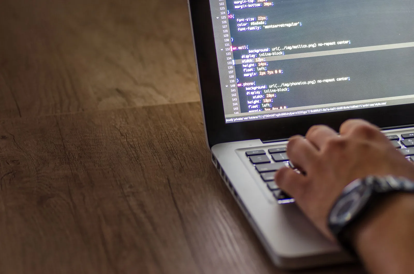 Developer working on laptop with code on screen, estimating custom software development costs